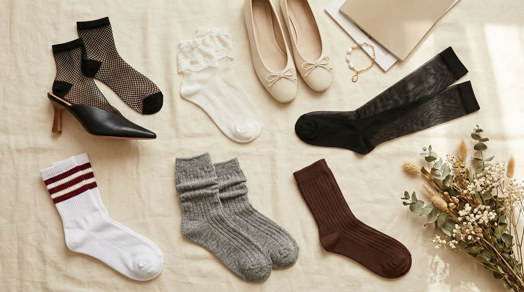 2026 sock trends flat lay: black fishnet ankle socks with heels, white lace ankle socks, ballet flats, sheer black knee highs, striped tennis socks, grey slouch socks and chocolate ribbed socks