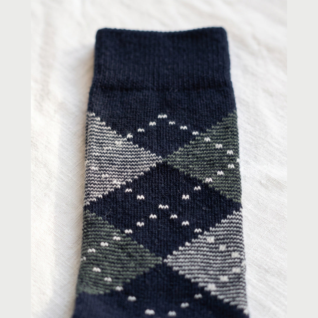 Close-up of navy argyle lambswool sock showing grey and green diamonds with white dotted outlines