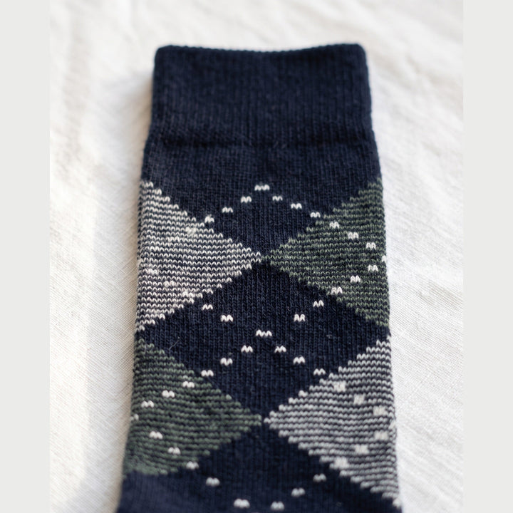 Close-up of navy argyle lambswool sock showing grey and green diamonds with white dotted outlines