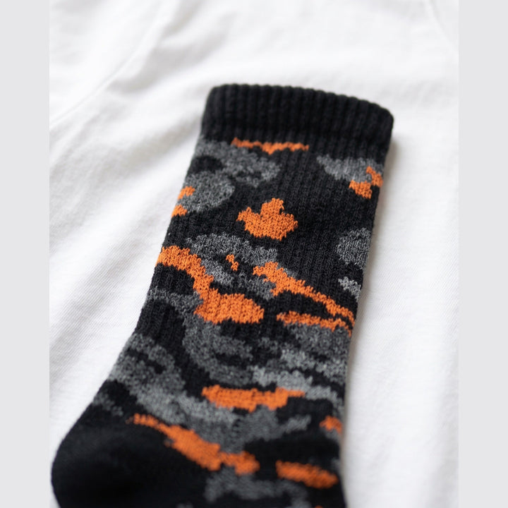 Close-up of black and orange knitted camo sock showing the ribbed cuff and camo knit