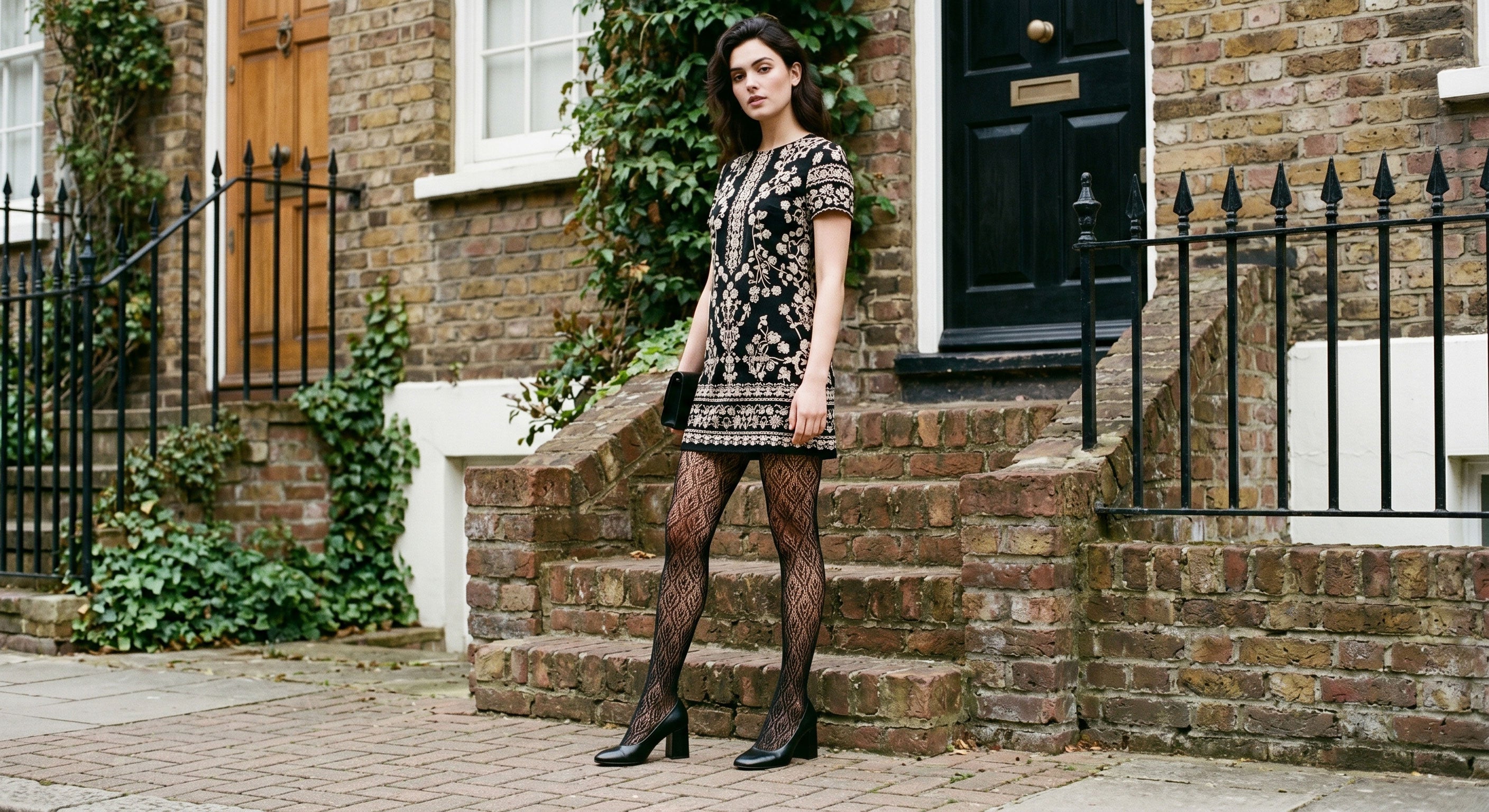 Elegant woman wearing black patterned fashion tights with embroidered mini dress and block heels, London townhouse, fashion editorial UK 2026