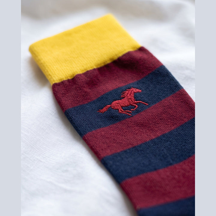 Close-up of burgundy and navy Galloper Rugby sock with yellow cuff and red embroidered galloping horse