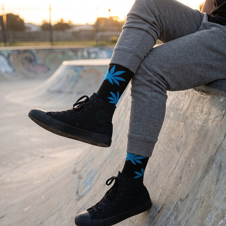 Man at a skate park wearing black leaf motif cushioned socks with grey sweatpants and black high-top sneakers