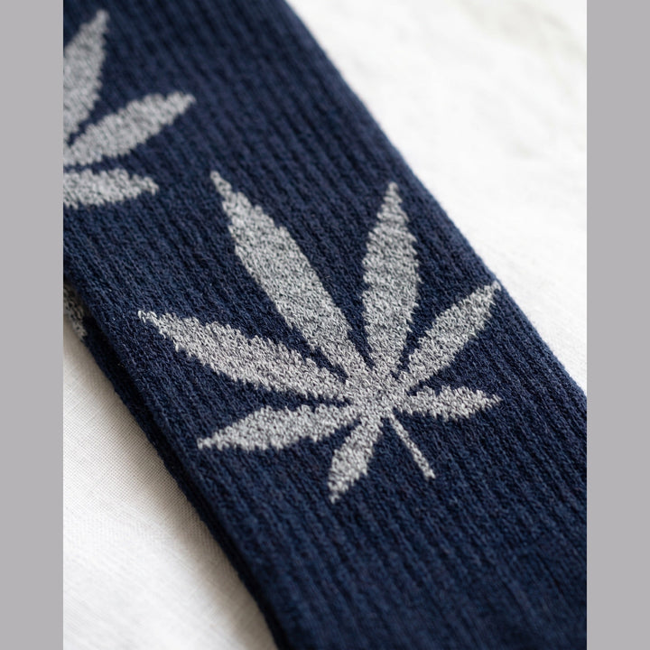 Close-up of navy sock with grey knitted leaf motifs and ribbed cuff