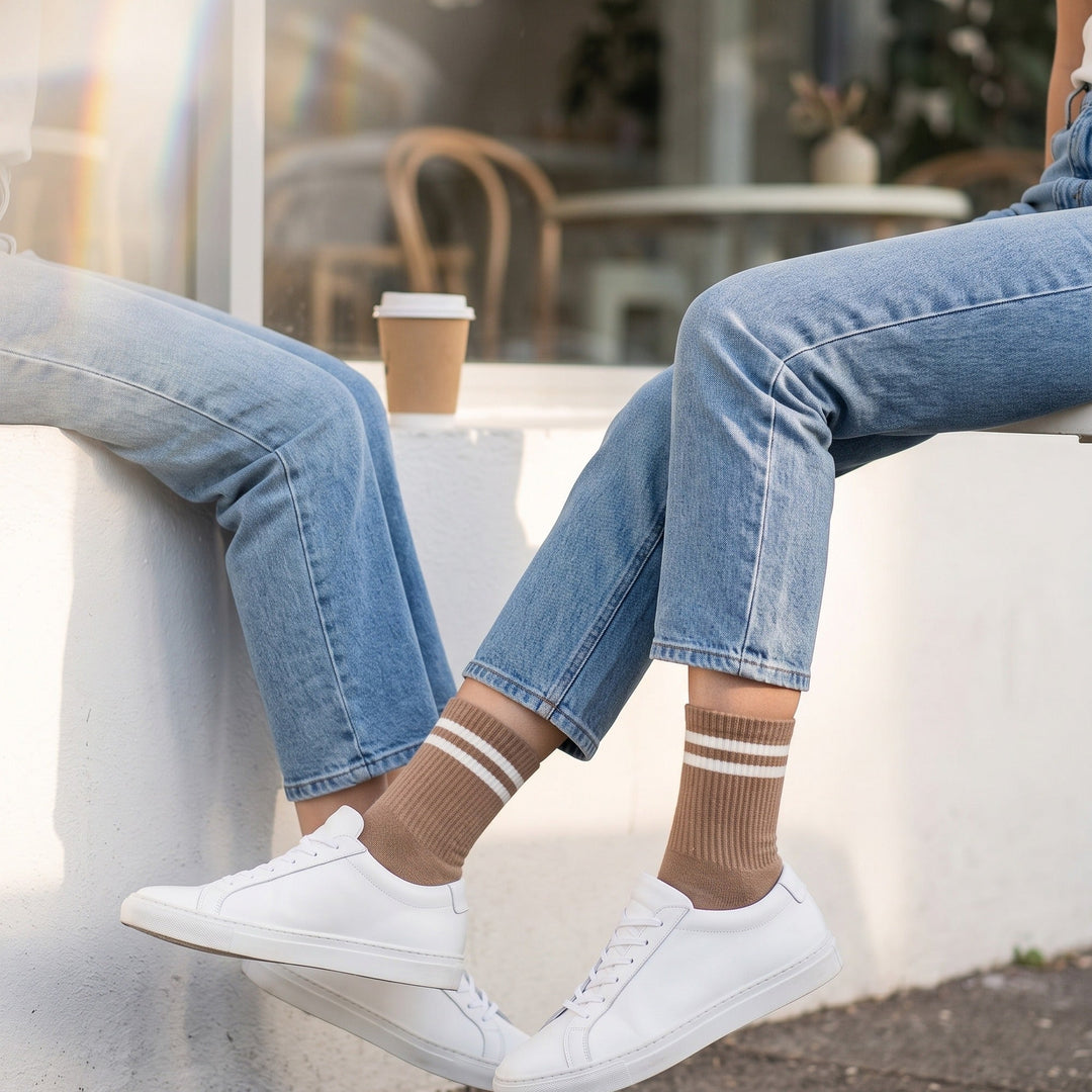 Woman outside a café wearing brown two-stripe tennis socks with light-wash jeans and white sneakers