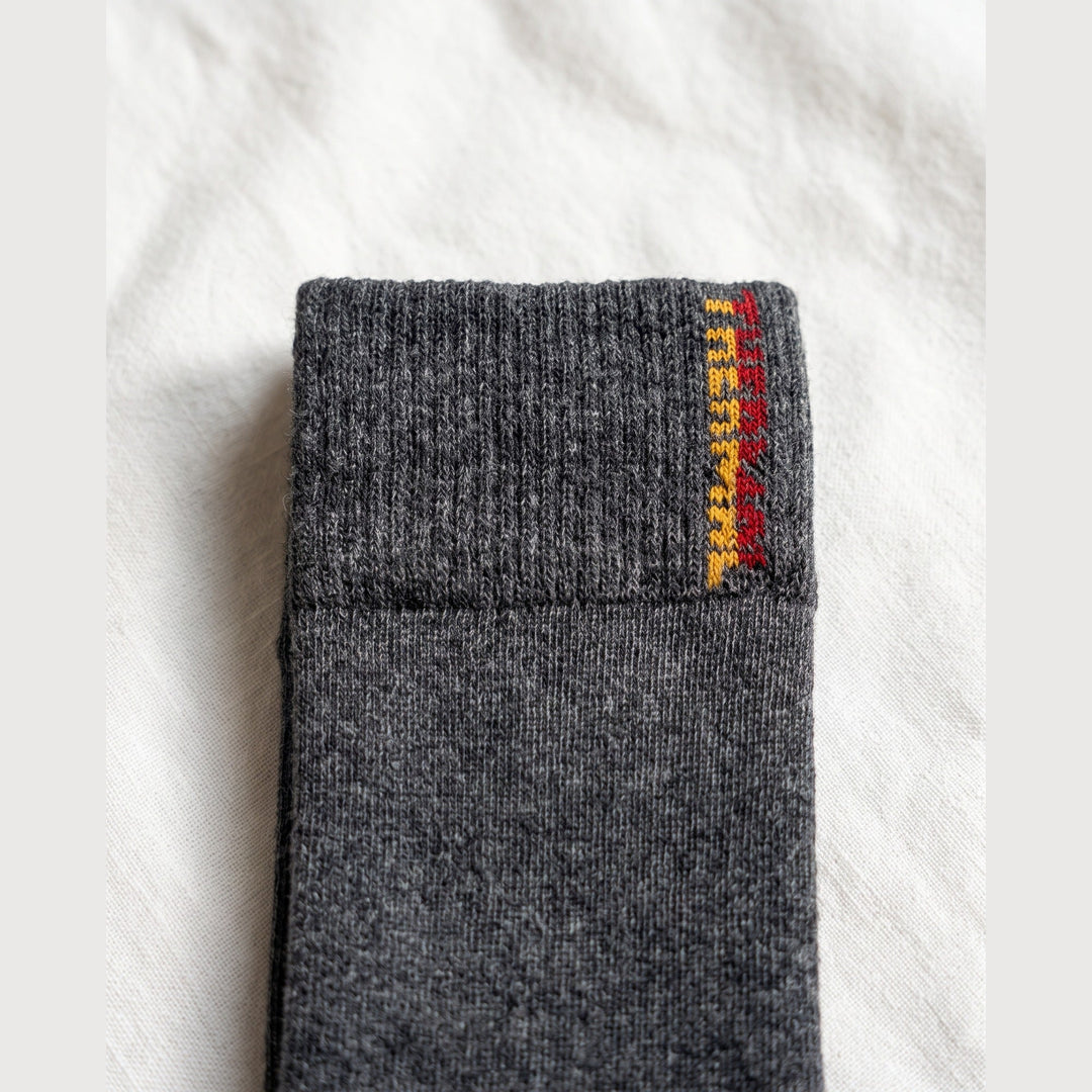 Close-up of charcoal Thermo sock showing the ribbed cuff and knitted yellow and red THERMO lettering
